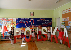 Dziewczynki z grupy Motylków stoja pomiedzy literami napisu Polska
