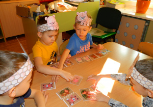 Dzieci siedzą przy stolikach i grają w misiowe memory