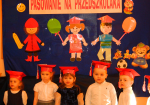 Dzieci z grupy Wiewiórek stoja na tle dekoracji i śpiewają piosenkę