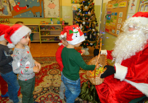 Mikołaj częstuje chłopców cukierkami