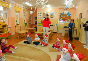 Dzieci śpiewają piosenkę dla Mikołaja i klaszczą w dłonie wrwaz z pania Izą i panią dyrektor