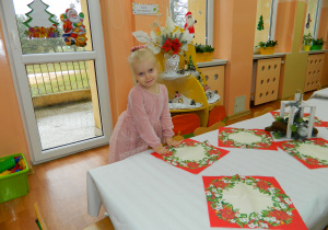 Dziewczynka rozkłada czerwone serwtki na stole