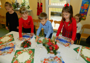 Dzieci z grupy Biedronek nakrywają stół do obiadu wigilijnego