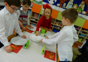 Dzieci z grupy Motylki rozkładają talerze na stolikach