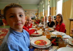 Widok dzieci z grupy Biedronek przy stole nakrytym odświętną serwetą i zapalonymi świecami