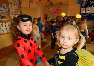 Dziewczynki w przebranich Biedronki i Pszczółki tańczą trzymając się za ręce