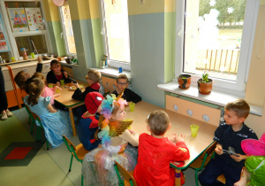 Dzieci z grupy Misiów siedza przy stolikach na słodkim poczęstunku