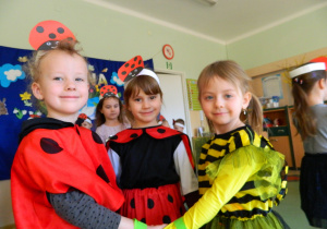 Dziewczynki w przebranaich biedronki i pszczoły tańczą tzrymając się za ręce.
