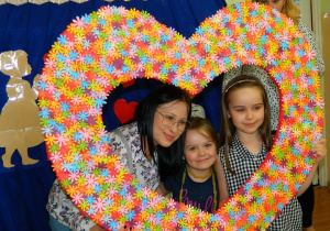 Dzieci z rodzicami pozuja do zdjęcia w ogronym kolorowym sercu.