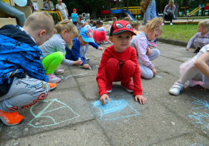 Dzieci malują kredą po chodniku.
