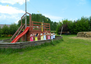 Przedszkolaki stoją w drewnianym statku.