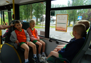 Dzieci jadą autobusem w strojach sportowych na zawody.