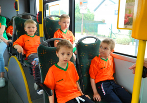 Dzieci jadą autobusem w strojach sportowych na zawody.