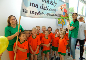 Pani dyrektor Marta Golis trzyma transparent wspólnie z dziećmi i panią Izą.