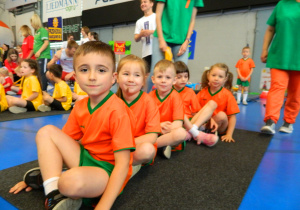 Dzieci oczekują na start zawodów siedząc na matach.