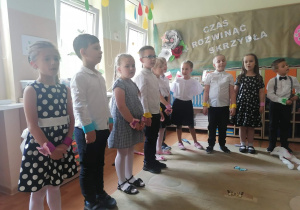 Dzieci stoją w półkolu i śpiewają piosenkę