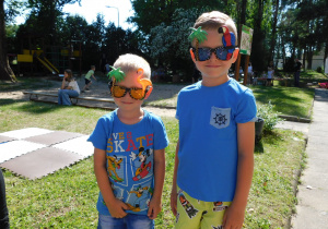 Chlopcy w ozdobnych okularach stoja w ogrodzie przedszkolnym.