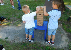 Chłopcy budują wieżę z drewnianych kolcków.