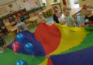 Dzieci podrzucaja kolorowe balony na chuście animacyjnej.
