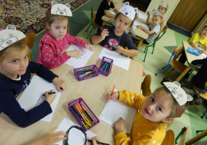 Dzieci z grupy Misiów siedza przy stolikach i malują.