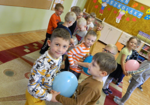 Chłopcy tańczą z balonem trzymając go brzuchem