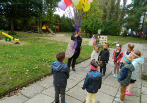Pani dyrektor rozdaje dzieciom balony z helem.