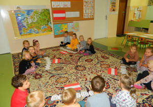 Dzieci z grupy Misiów siedzą na dywanie przed napisem Austria i flagą tego kraju