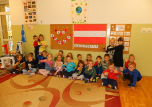 Dzieci z grupy Jeżyków pokazują duża flagę Austrii na dekoracji.