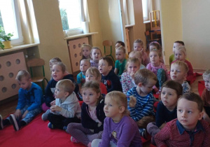 Dzieci siedzią na podłodze słuchając wykładów Pani leśnik