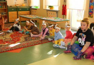 Pani Jesień ma założone kalosze na dłonie i bawi się z dziećmi siedzącymi na dywanie