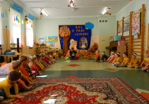 Przedszkolaki siedzą i trzymając ręce na podłodze w zabawie o kaloszach