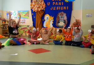 Biedronki i Misie podnoszą ręce do góry podczas zabawy na dywanie z panią Jesień