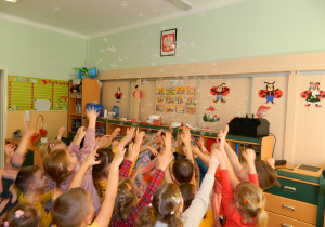 Dzieci wyciągają ręce do baniek mydlanych