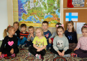 Dzieci z grupy Misiów siedzą na dywanie , w tle mapa świata