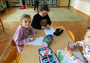 Dziewczyny siedzą przy stoliku i kolorują postać muminka
