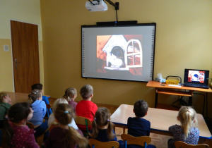 Przedszkolaki oglądaja na tablicy multimedialnej bajkę "Muminki"
