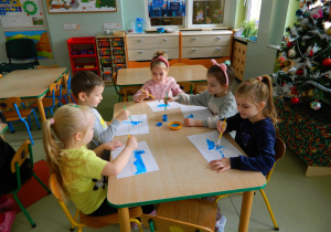 Dzieci przy stolikach malują farbami flagę Finlandii