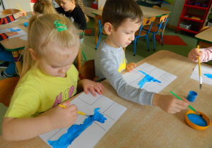 Dzieci przy stolikach malują farbami flagę Finlandii