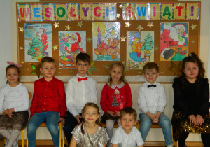 Dzieci z grupy Motylki na tle dekoracji "Wesołych świąt"