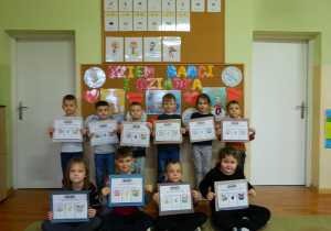 Dzieci z grupy Motylki trzymają w rękach upominki kalendarze dla Babci i Dziadka
