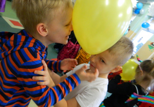 Chłopcy trzymają balon pomiedzy swoimi czołami w konkursie