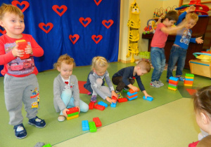 Dzieci z różnych grup rywalizują w układaniu wieży z klocków.