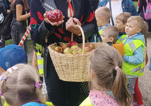 Pani dyrektor stoi wśród dzieci i trzyma w dłoni jabłko