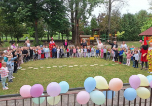 Widok wszystkich dzieci wraz z paniami w ogrodzie przedszkolnym