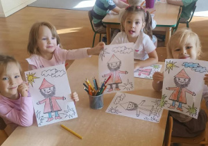 Dziewczynki siedzą przy stoliku i kolorują Krasnala Hałabałę