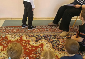 Chłopiec stoi przy tablicy z napisem Dzień Zyczliwości.