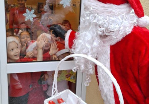Mikołaj zagląda przez okno do przedszkola.