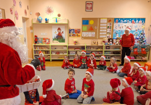 Mikołaj odwiedza grupę Biedronki, dzieci siedzą na dywanie.