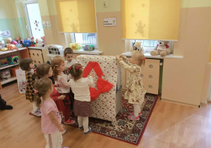 Maluchy wspólnie odpakowuja prezent od Mikołaja.