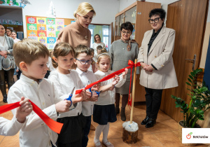 Dzieci przecinają wstęgę otwracia bibiloteki.
